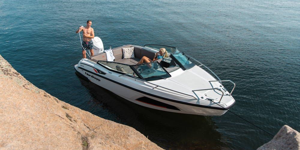 Nordkapp Noblesse 660 moored next to rocks with man using shower