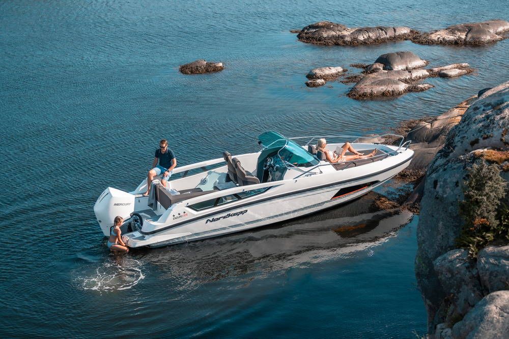 Nordkapp Enduro 805 moored next to rocks on calm water with people swimming